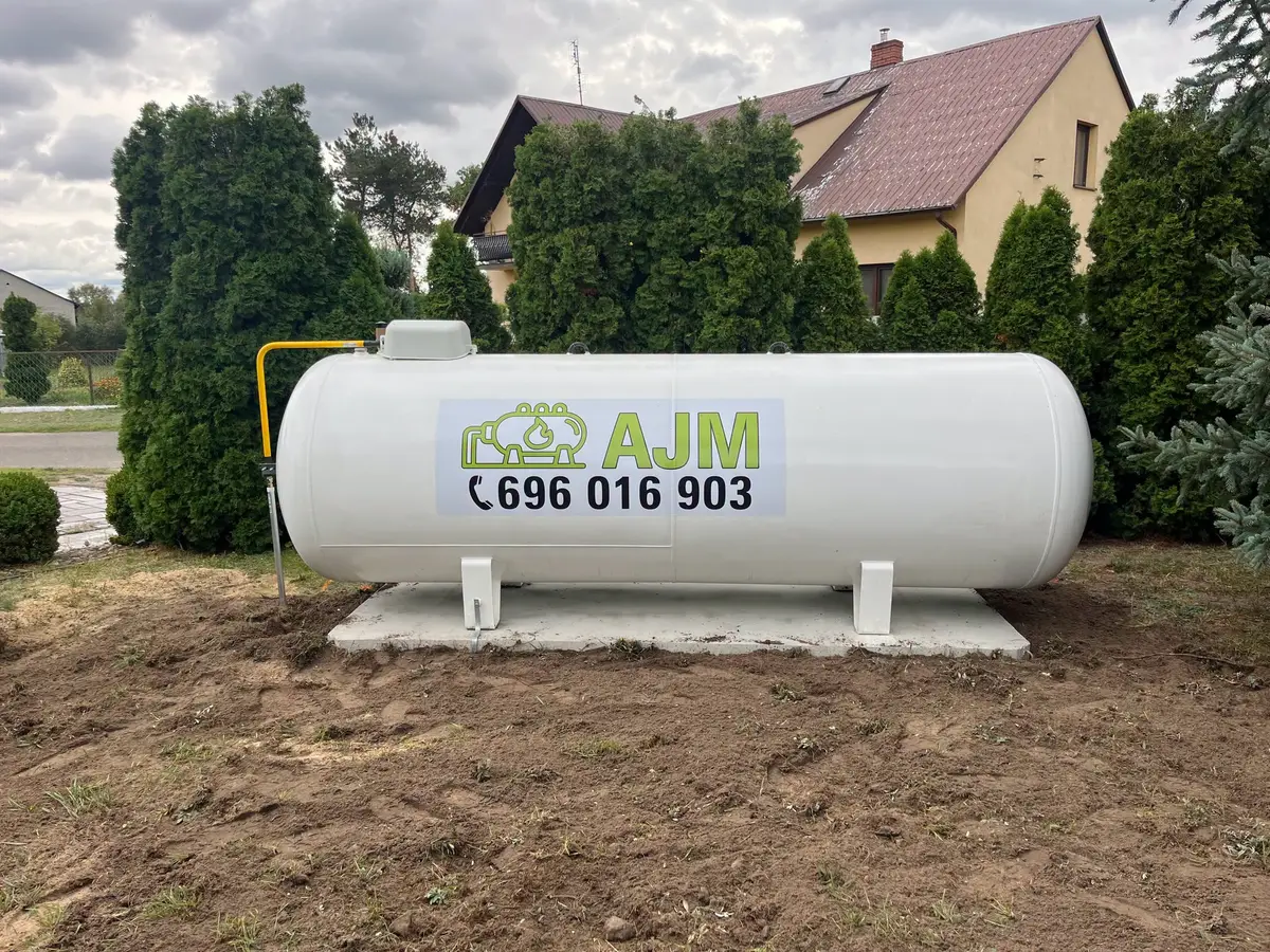 Biały zbiornik LPG z naklejką AJM przy domu w Kobylanach