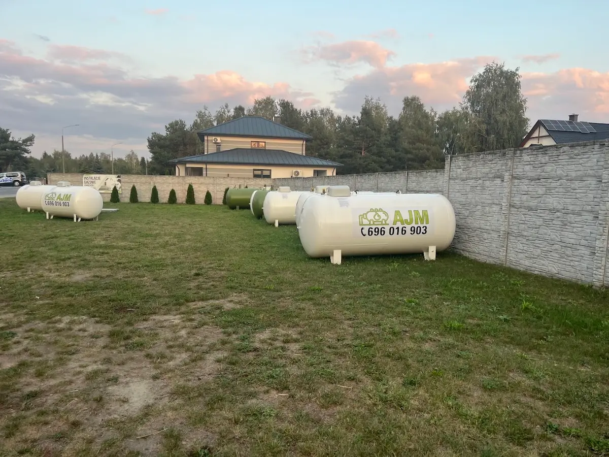 Plac z kilkoma zbiornikami AJM przygotowanymi do montażu, wieczorne niebo